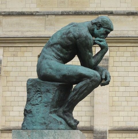 A photo of the bronze statue "The Thinker" by Auguste Rodin. It shows a nude man crouched over, deep in thought. His back is in flexion, which Stuart McGill would not recommend.
