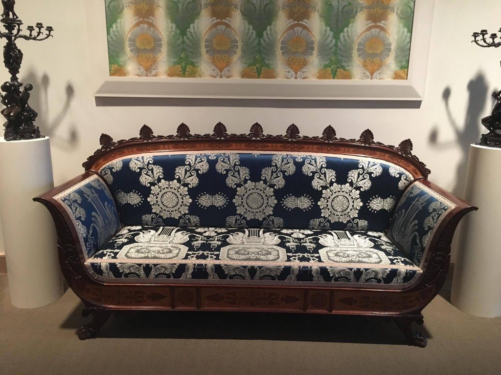 This photo, taken at the Metropolitan Museum of Art in New York City, features a couch with carved wood arms and back, and patterned blue-and-while upholstery. There is some historical significance, but I frankly don't remember what it is.