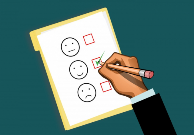 An illustration of a man's hand poised over a survey with a happy face, a neutral face, and a frowny face. He holds a pencil, and is checking the box by the smiley face.
