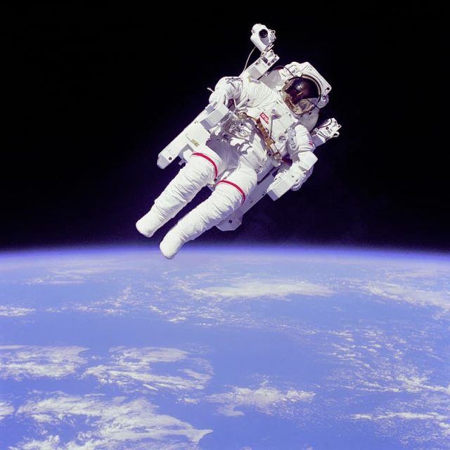 An astronaut in a spacesuit floats above the Earth.