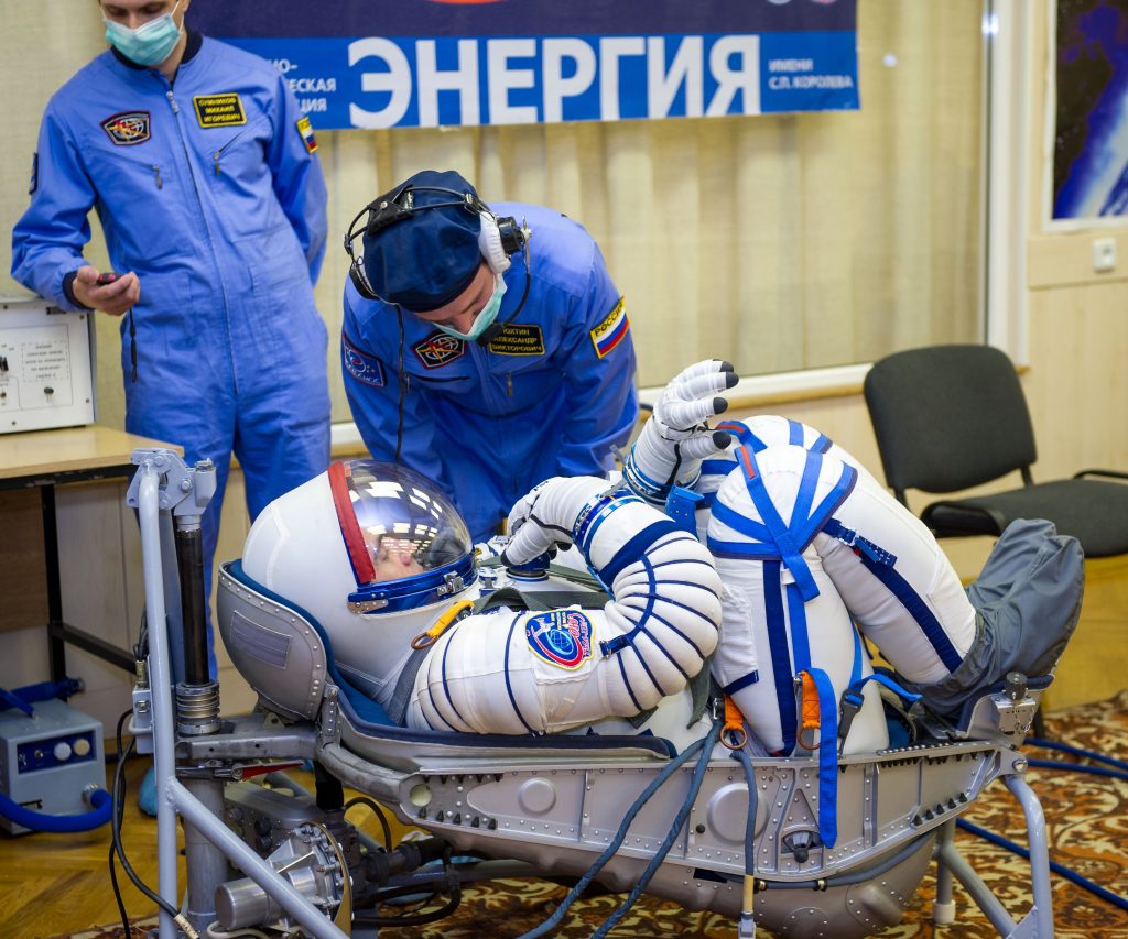 A NASA astronaut curls up in his seat during pre-flight checks. He is destined to launch in the Soyuz spacecraft and arrive at the International Space Station. This photo was taken in 2013.