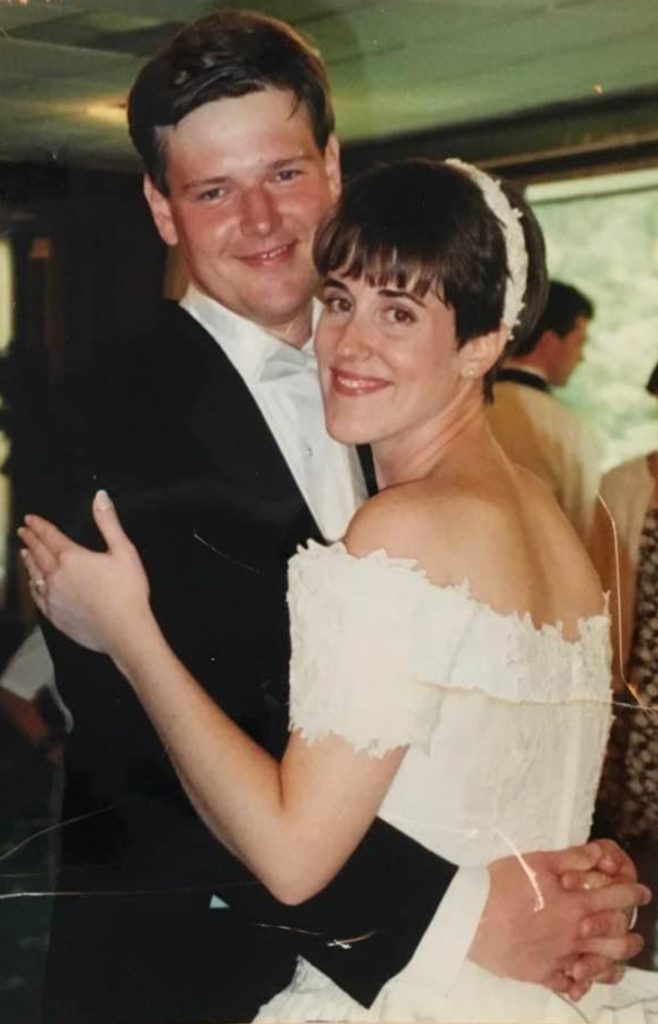 A faded photo from Claire and Tom's wedding. His arms are clasped around her waist, and she's holding his arms. Maybe they're dancing? They're both dressed up fancy, and smiling. 