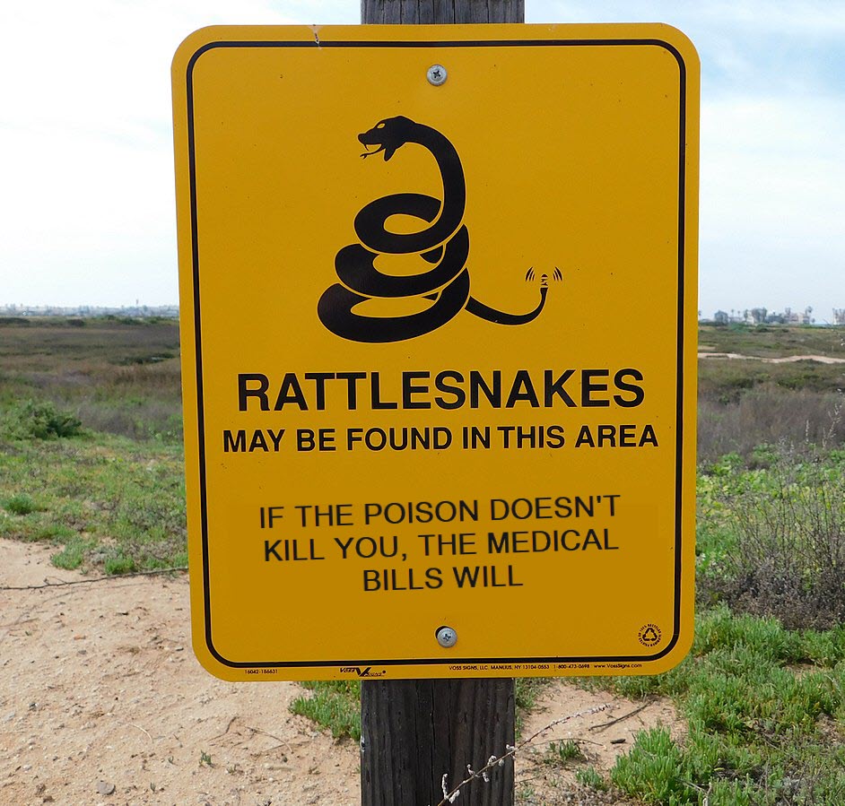A photo of an orange trail sign, with the desert visible in the background. The sign has a black drawing of a rattlesnake. Below it is written, "RATTLESNAKES MAY BE FOUND IN THIS AREA. IF THE POISON DOESN'T KILL YOU, THE MEDICAL BILLS WILL"