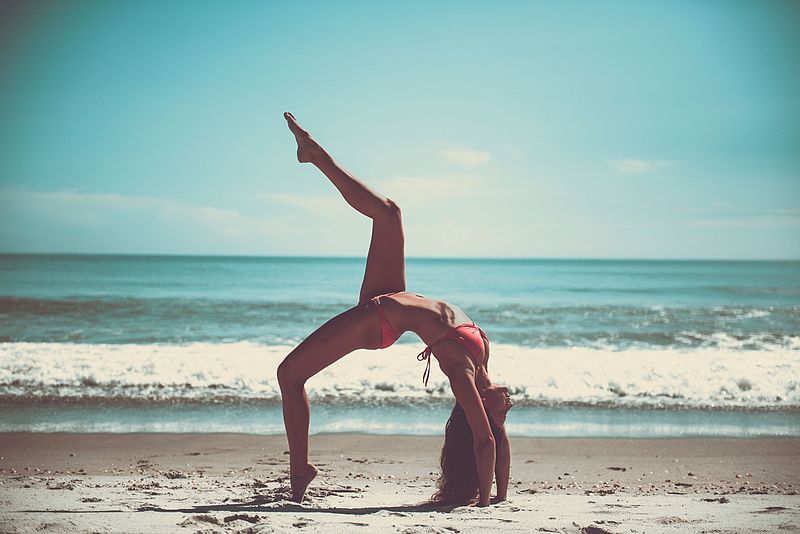 A photo of an attractive woman doing the yoga wheel pose on the beach. She has one leg in the air, which doesn't seem like an authentic yoga thing to me, but what do I know? Her toes are pointed, so maybe she's a dancer. It's a gloriously sunny day, and the ocean looks placid.  Really, this is a wonderfully cliche photo that should represent freedom, but makes me consider how comparatively stiff I am. I pity her facet joints.