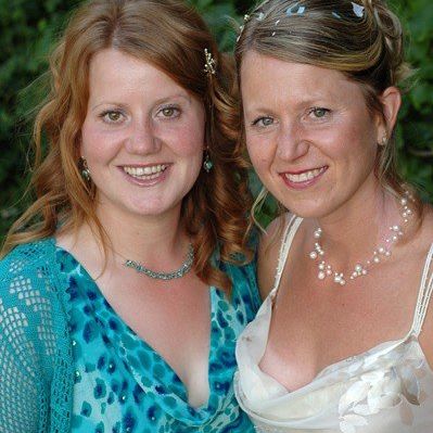 This photo of Julie and her sister, Shelly, was taken in 2005 at Julie's wedding. Shelly is on the left. She's wearing a blue dress and a shrug. Julie is on the right, wearing her wedding dress. Shelly has reddish hair, and Julie is a dark blonde, but the family resemblance is obvious.