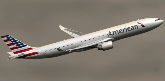 This photo shows a large passenger jet flying. The logo for American Airlines is painted on the front of the jet, and the tail is painted red, white, and blue. The sky is dimly gray and cloudy.