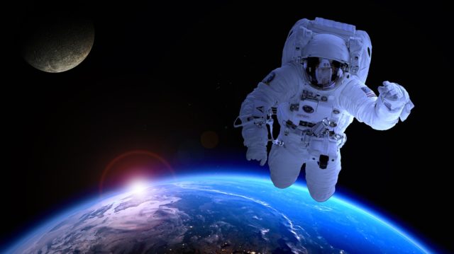This image, which could not possibly be Photoshopped, shows an astronaut floating over a brilliantly blue Earth. The sun is just setting at the horizon, and casts a halo around itself and an aura above the Earth. The moon -- or a moon, since it doesn't look much like Earth's moon, although maybe it is -- is floating in the top left.