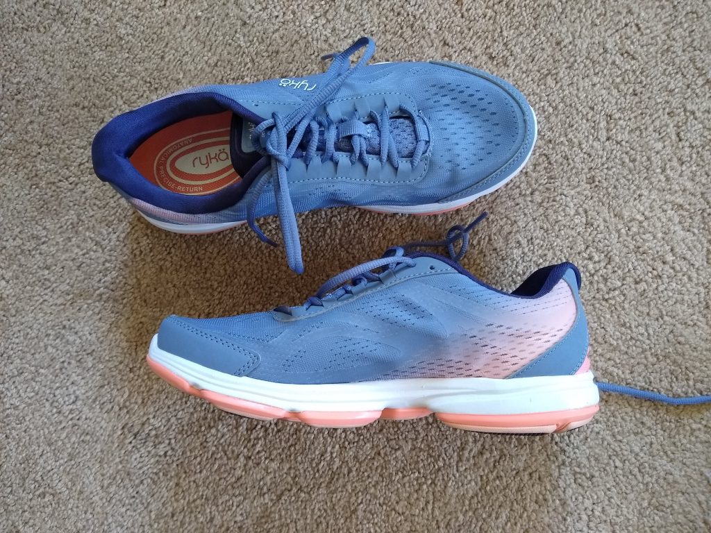 A photo of a pair of walking shoes. The left shoe is on top, photographed from above. The right shoe is underneath, photographed from the side.
